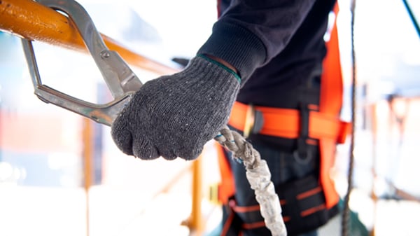 O trabalhador da construção civil usa arnês de segurança e linha de segurança trabalhando em um novo projeto de canteiro de obras.