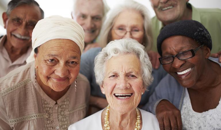 Um grupo de idosos sorrindo juntos em uma casa de repouso