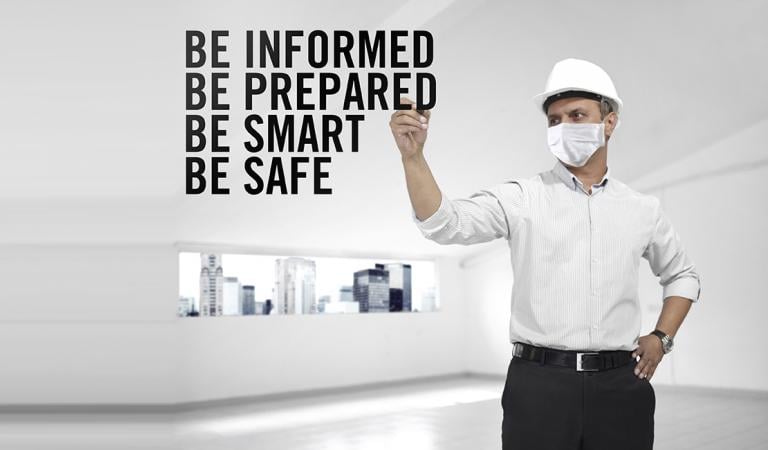 Architetto che indossa una maschera medica scrivendo precauzioni pandemiche in aria in un edificio vuoto