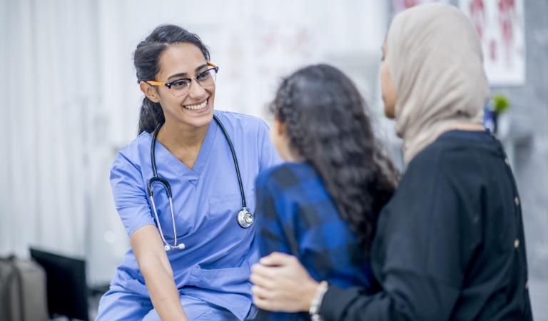 An Ethnic doctor is indoors in a hospital room. She is trying to cheer up a young girl, who is nervous about her checkup. Photo: iStockphoto